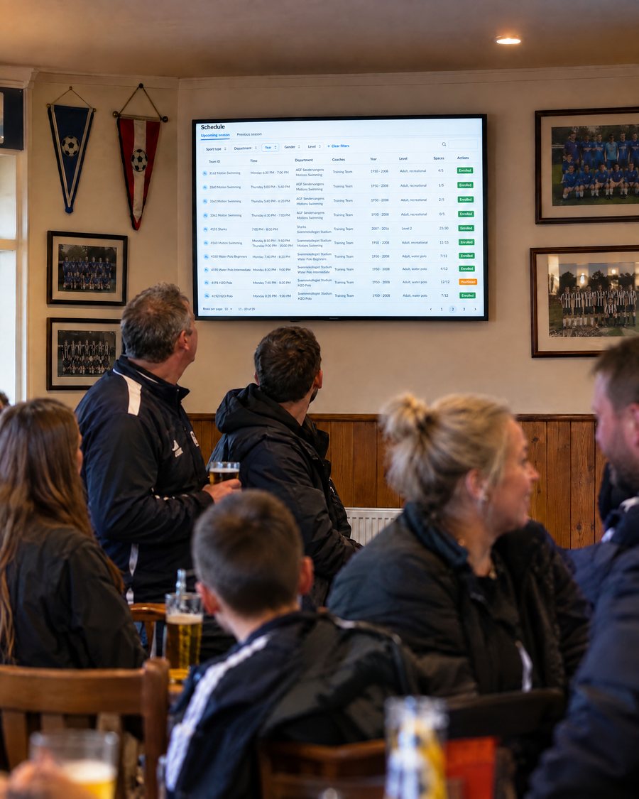 Members in the clubhouse following the club’s teams and training times on the SportMember info screen
